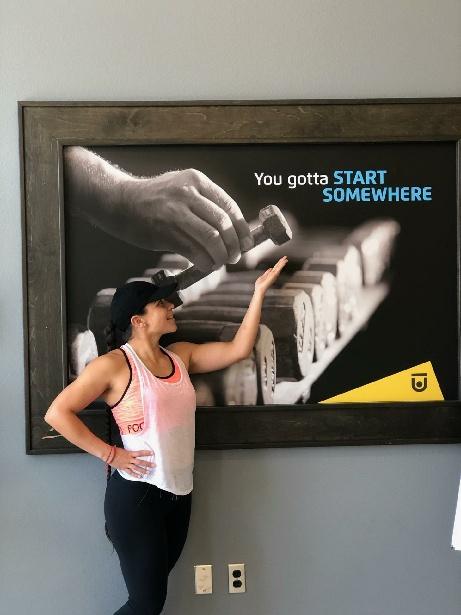 Group X Instructor, Blanca Ramirez, in front of some art at Chuze Fitness that says "You gotta start somewhere"