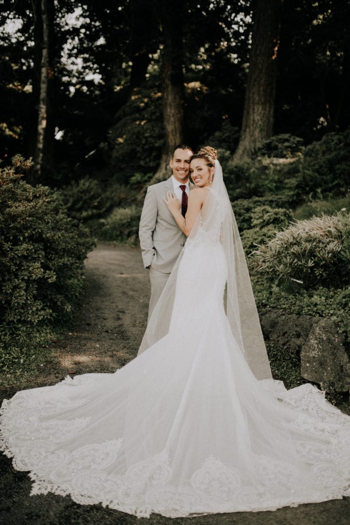 Chase Pantoja and Melissa Pantoja in a forest in Portland posing for photos on their wedding days. Melissa's gown is sweeping across the forest floor.