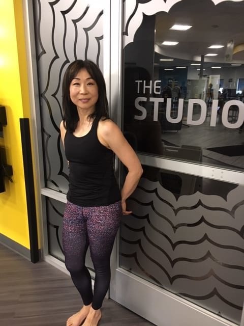 Yuko Caruso, The Studio instructor standing in front of the front door of the heated studio at Chuze Fitness