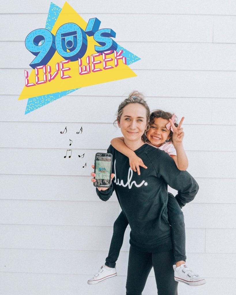 Aly and her daughter posing in front of a white wall with the 90's Love Week logo overhead